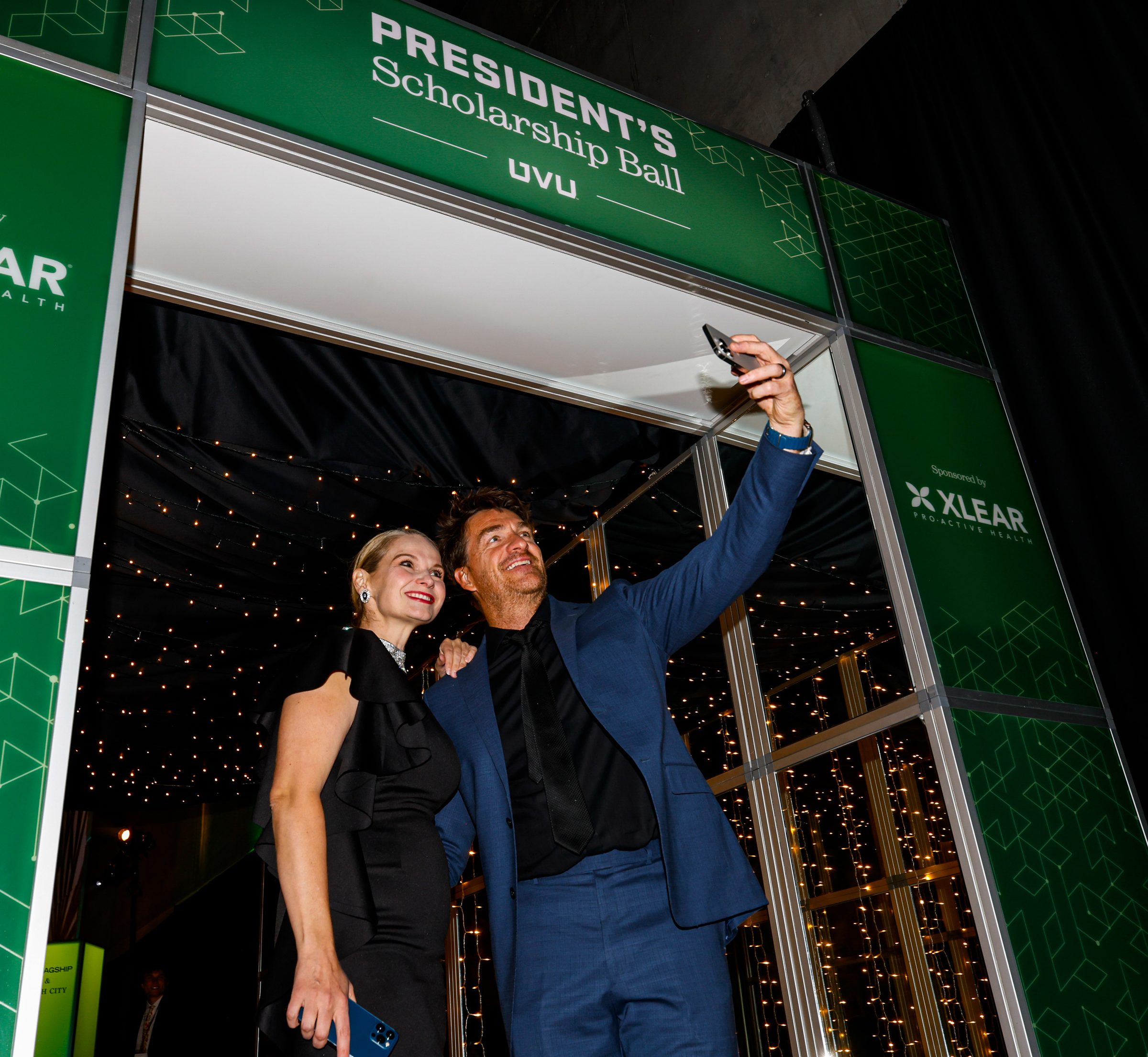 Guests taking a selfie under the green President's Scholarship Ball entrance arch