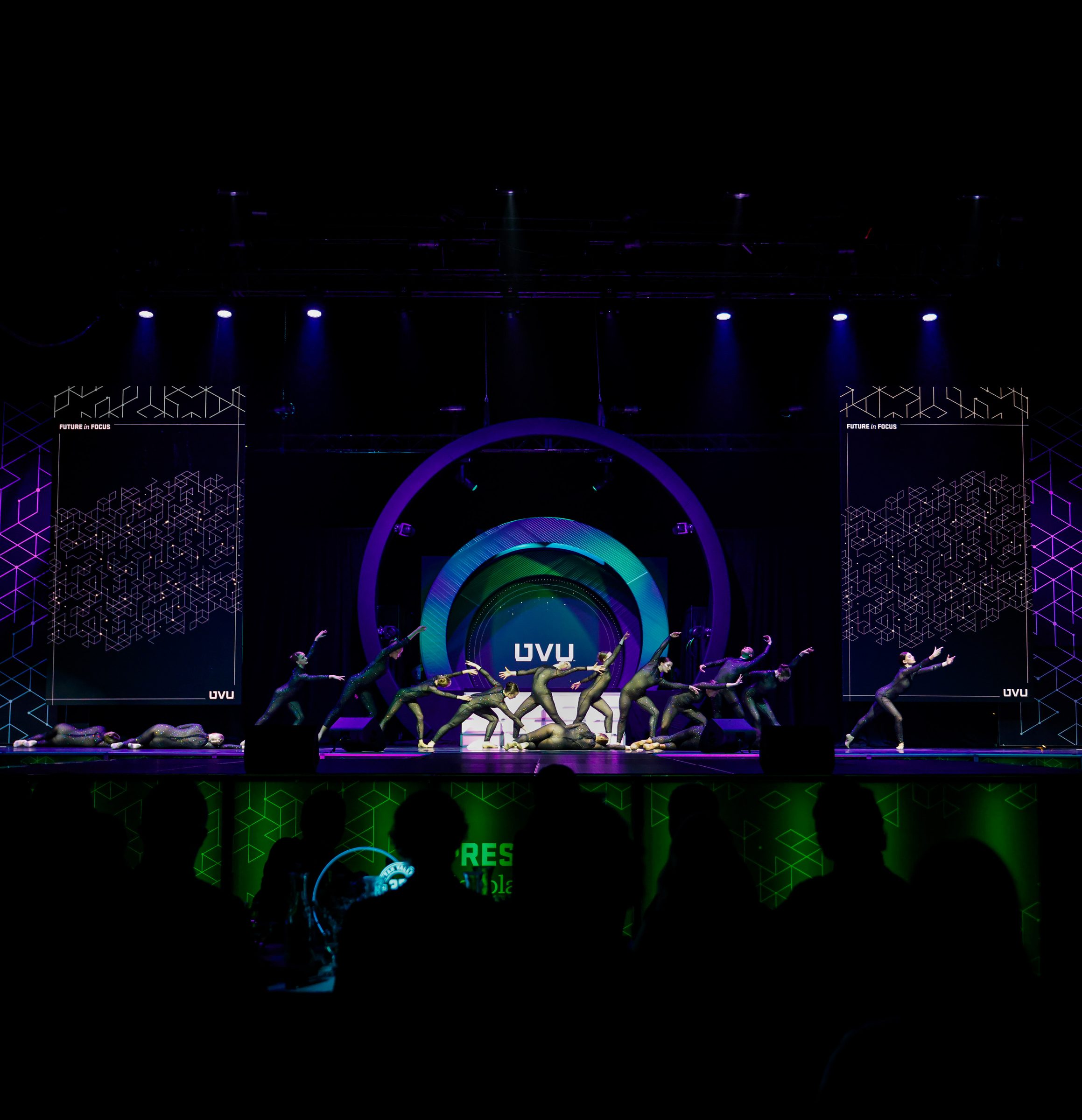 Dancers on the PSB 2026 stage in front of the glowing UVU focal ring, flanked by Future in Focus hex-grid screens
